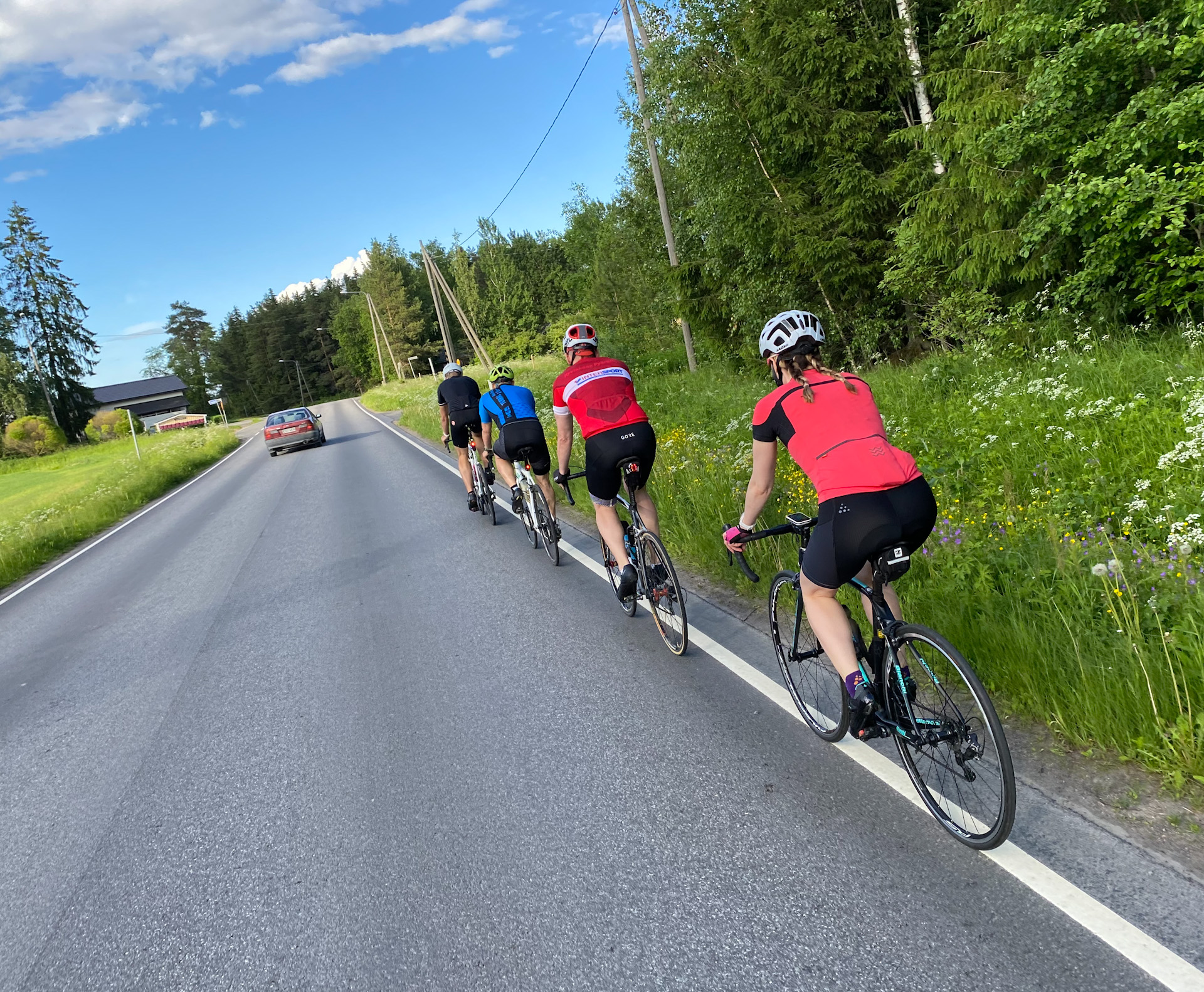 pyöräilijöitä ajamassa tien oikeassa reunassa kirkkaana kesäpäivänä