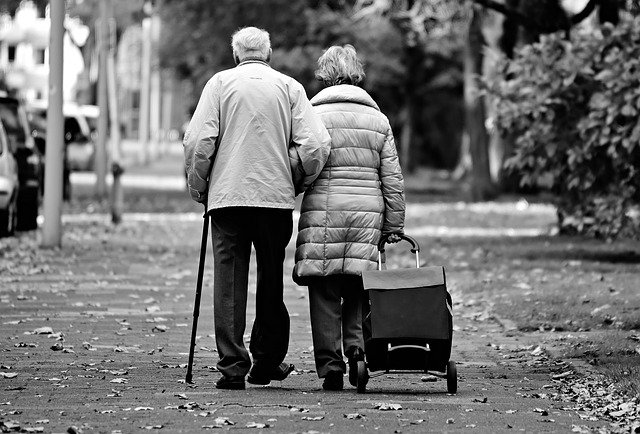 vanha mies ja  nainen kävelee vetäen rullakassai