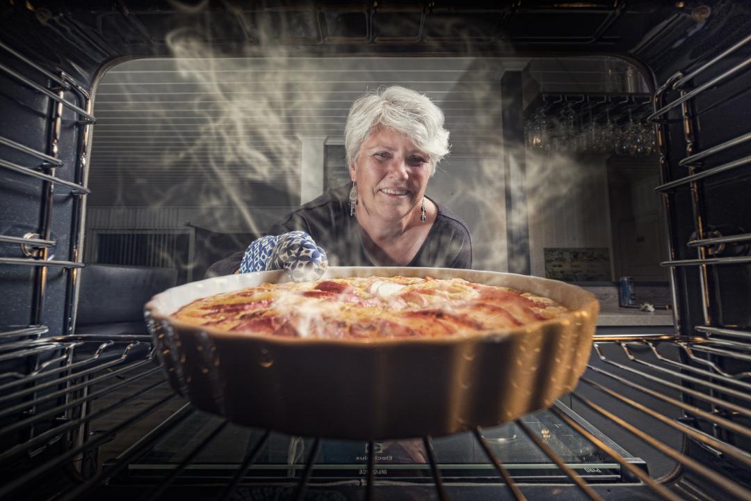 nainen laittaa uuniin piirakkavuokaa