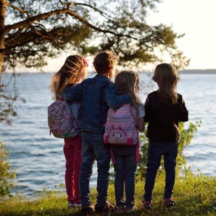 teksti pidetään huolta toisistamme, kotimaanapu, neljä lasta seisoo veden äärellä selin